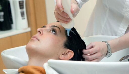 Der Meister trägt das Produkt auf, während es durch das Haar geht.